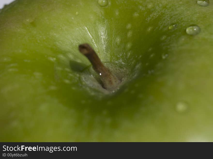 A closeup of a green apple with water droplets.