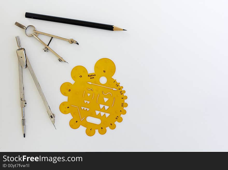 Drafting instruments and a radius stencil on a piece of paper. Two pairs of compasses a stencil and a pencil are laid out in a symmetrical pattern. Drafting instruments and a radius stencil on a piece of paper. Two pairs of compasses a stencil and a pencil are laid out in a symmetrical pattern.