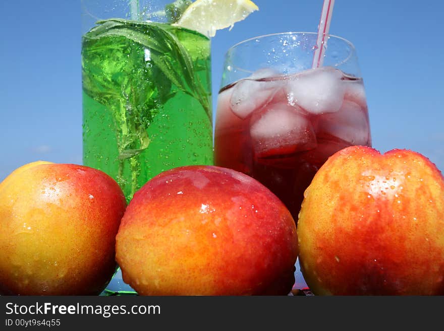 Green and red drink with icecubes in glasses on the blue sky backgraunds. Green and red drink with icecubes in glasses on the blue sky backgraunds