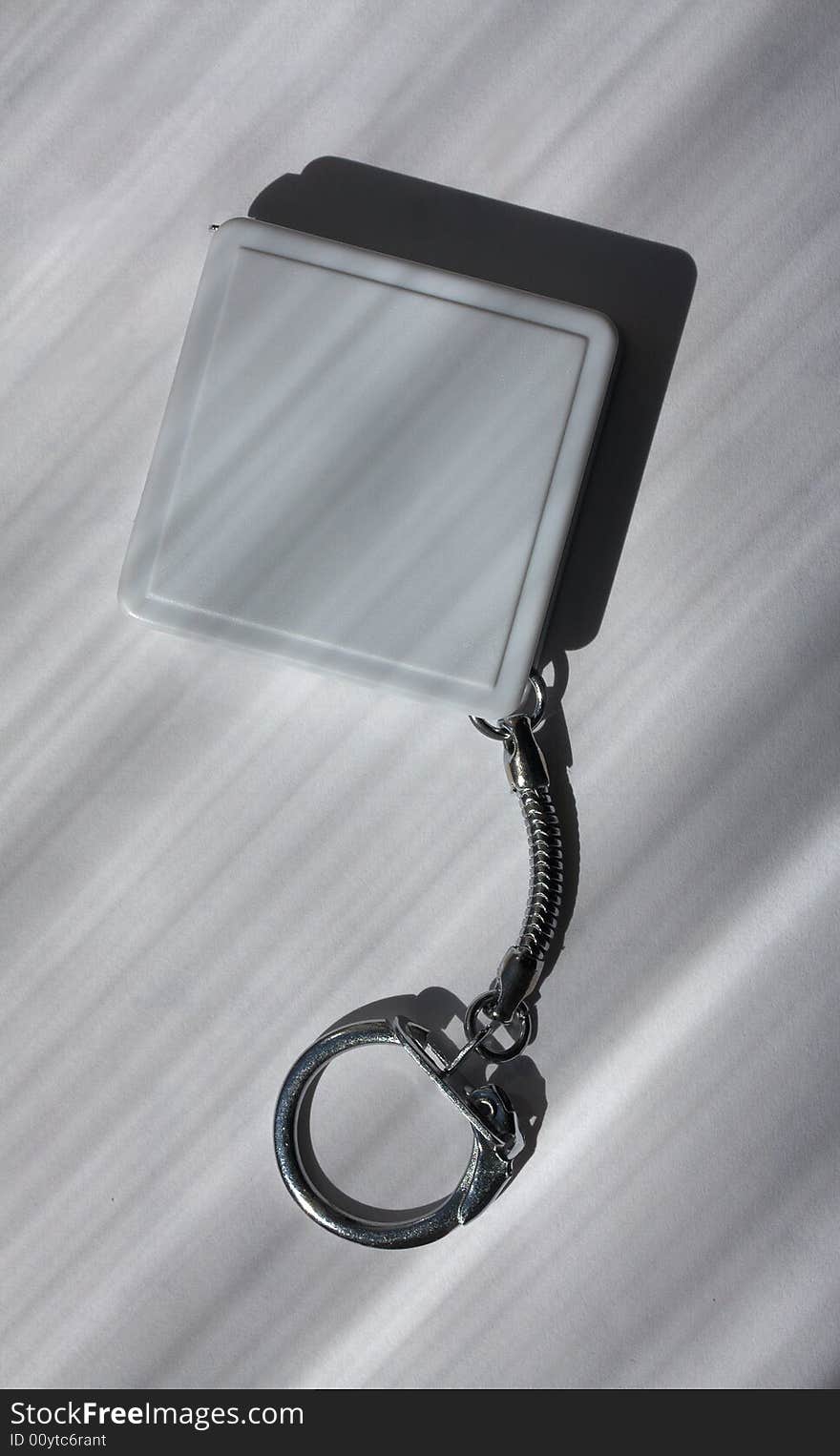 A square plastic charm of grey color on a metal chain with the lock