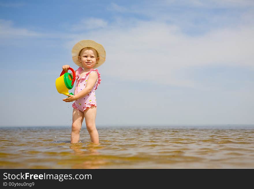 Small girl with watering-pot on the seashore. Small girl with watering-pot on the seashore