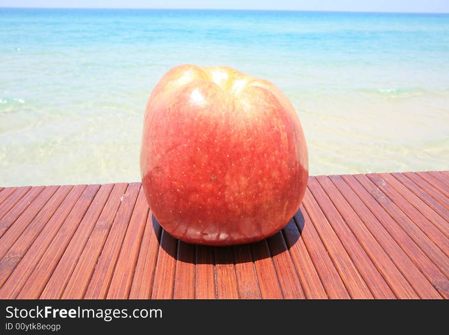 Big red apple on the wood table on the backgraund warm sea