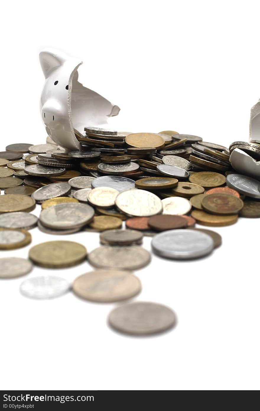 A broken piggy bank isolated on a white background with loads of coins from around the world. A broken piggy bank isolated on a white background with loads of coins from around the world.