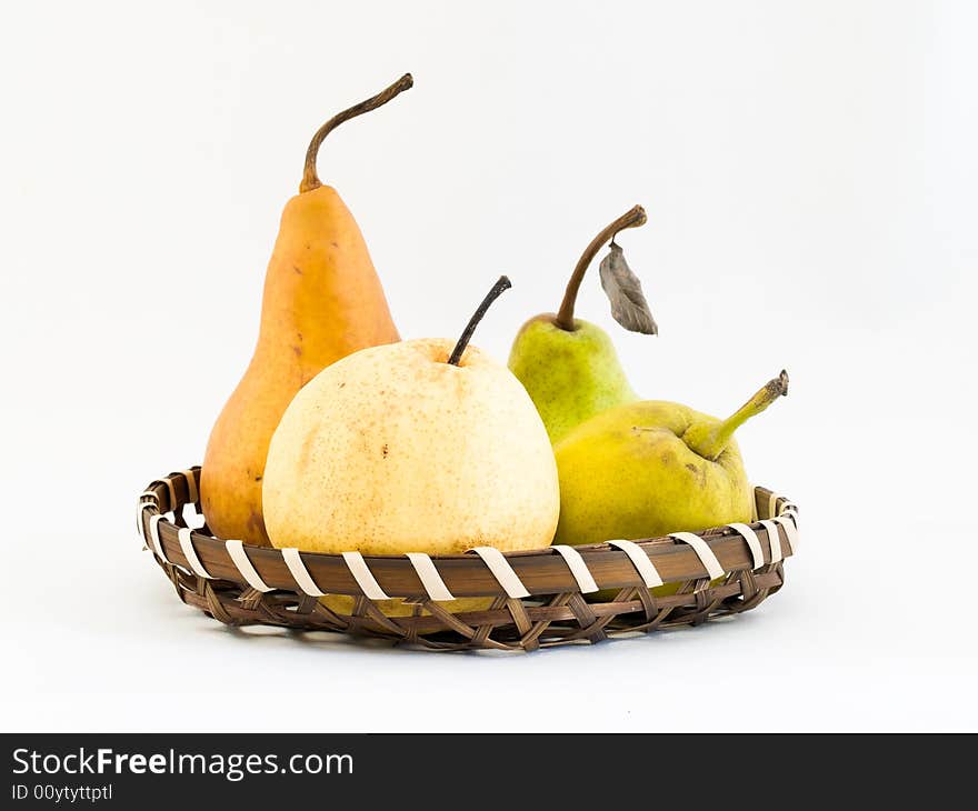 Still life of four types of pears in a wicker basket, namely a Bosc, a Packham, and two Asian pears, a Gong and the fragrant pear.