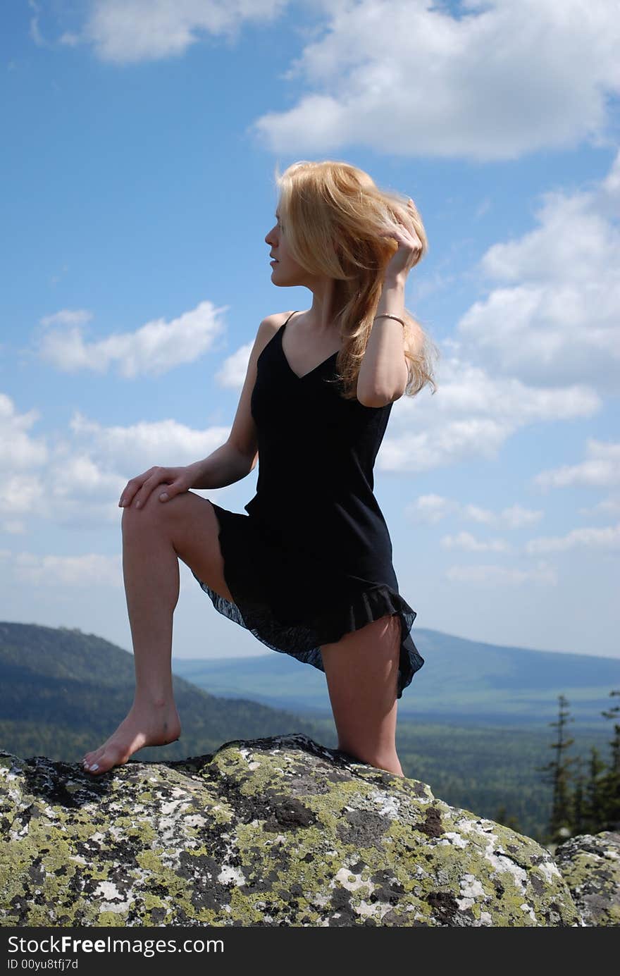 Sexy woman in the black dress on rock