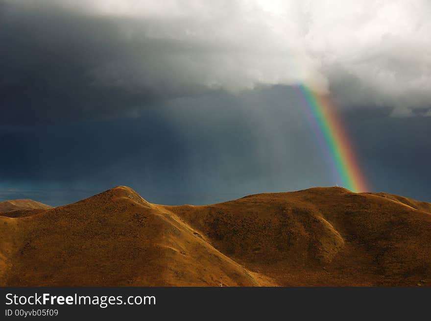 After the rain, a rainbow appear atop the hill. After the rain, a rainbow appear atop the hill