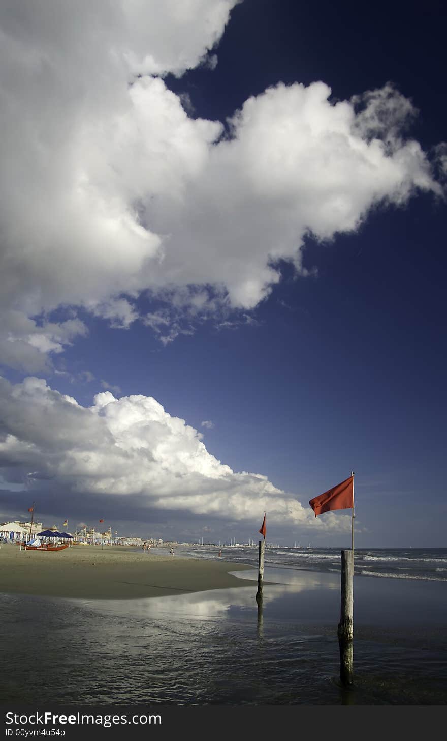 White Cloud In Ablue Sky over a beautiful beach with red security flag in the sea