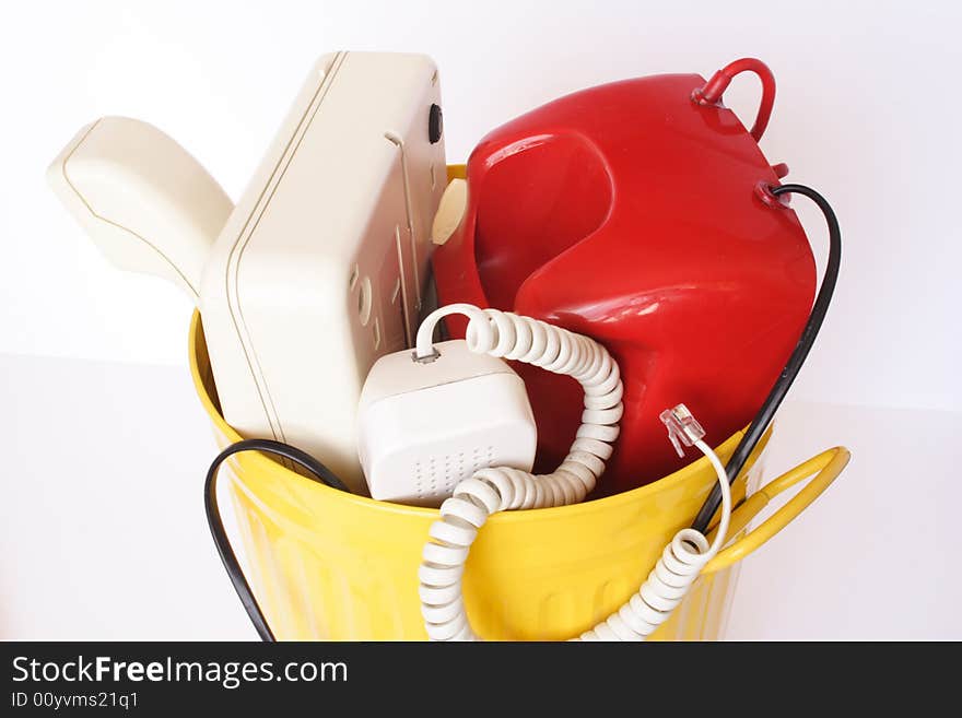 Old telephones in the yellow dustbin isolated. Old telephones in the yellow dustbin isolated