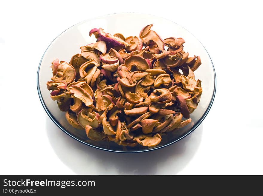 Dry slices of apple on a glass plate on white background