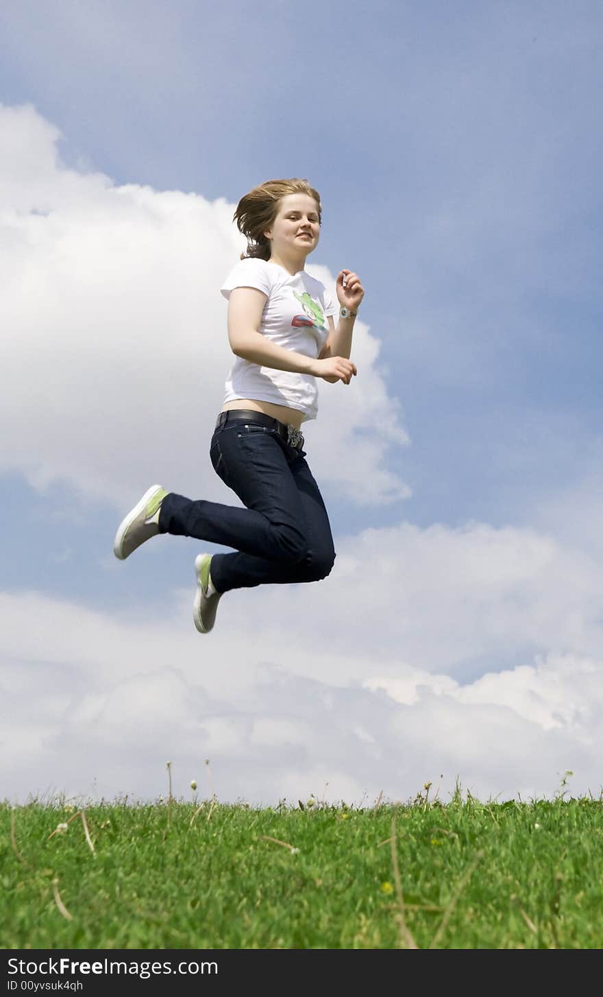 The happy jumping girl on a background of the blue sky