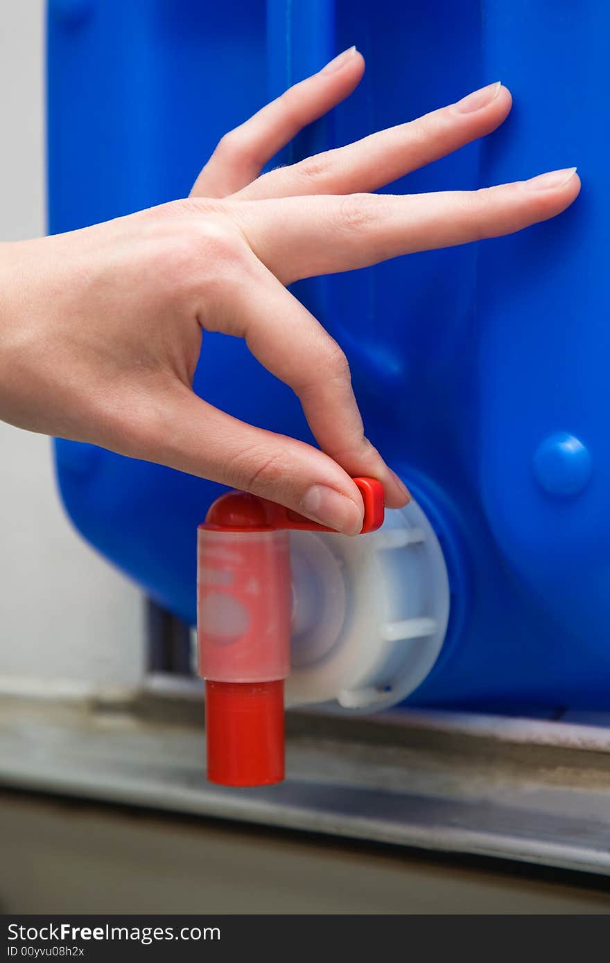 Hand on the red valve of the blue tank; Shallow depth of field. Close-up. Hand on the red valve of the blue tank; Shallow depth of field. Close-up.