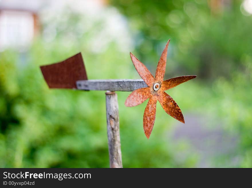 Rusty weather-vane on green smooth background