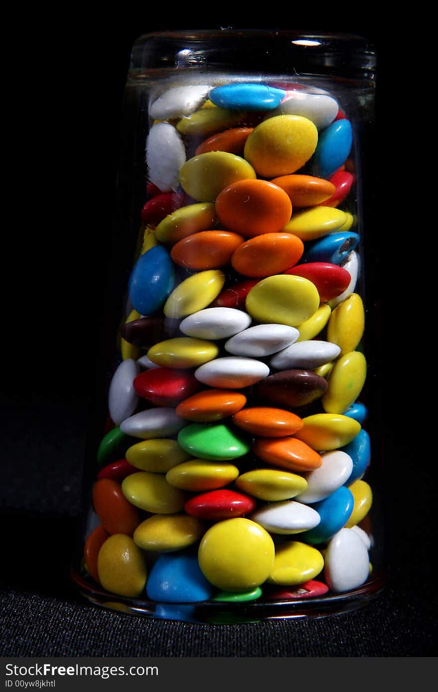 Many colored candies and a glass