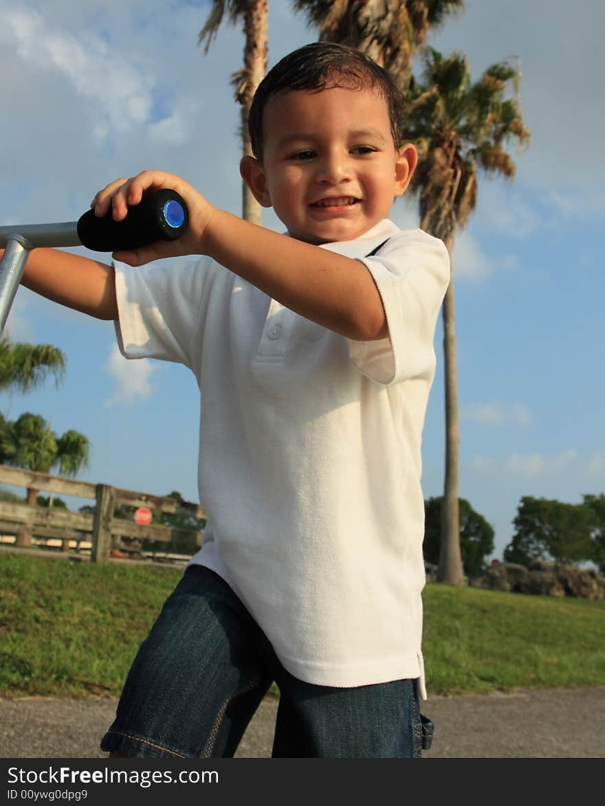 Young boy smiling and holding on to his scooter. Young boy smiling and holding on to his scooter.