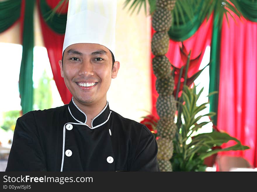 Chef smiling, decorated pineapple at background