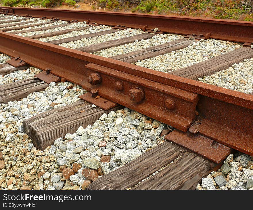 Rusty railroad, unused for a long time, with wooden ties. Crushed stone  track ballast neatly placed between the ties.