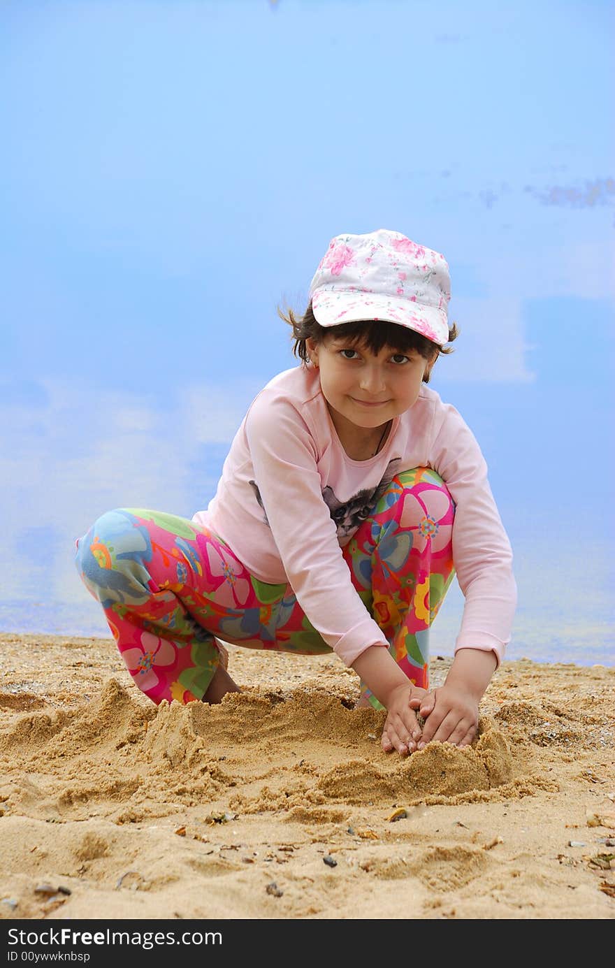 Child on river shore play in sand