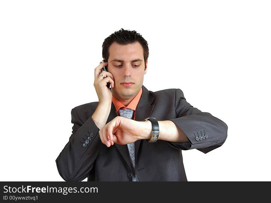 A young businessman, talking over the phone, while looking at his wrist watch. A young businessman, talking over the phone, while looking at his wrist watch