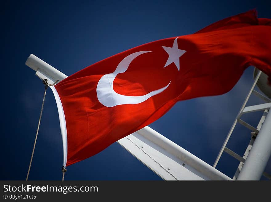 Turkish flag on flagstaff streaming on the wind on the blue sky background

. Turkish flag on flagstaff streaming on the wind on the blue sky background