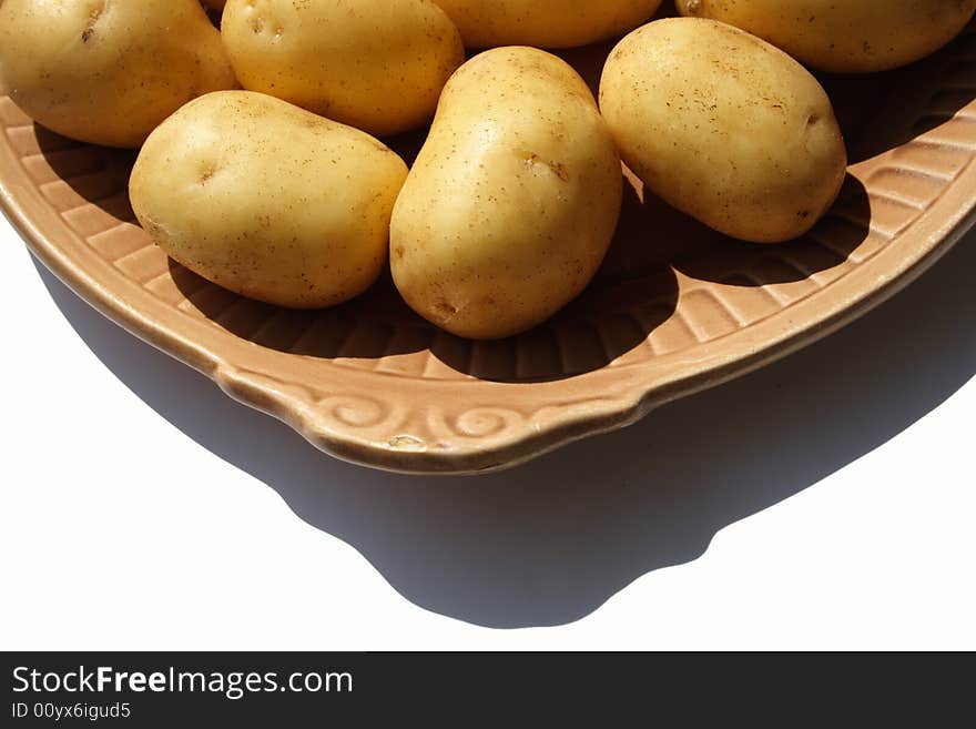 Potato on brown ceramick plate  isolated on white background. Potato on brown ceramick plate  isolated on white background