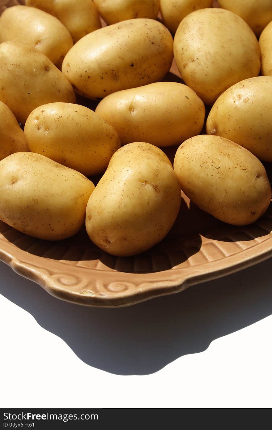 Potato on brown ceramick plate  isolated on white background. Potato on brown ceramick plate  isolated on white background