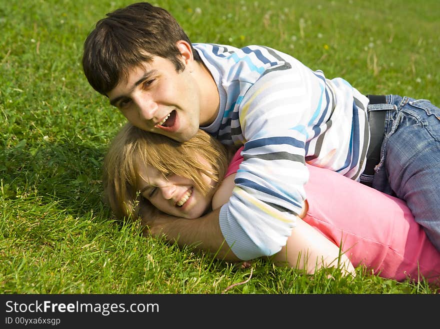 Young Happy Couple Laying On A Green Grass