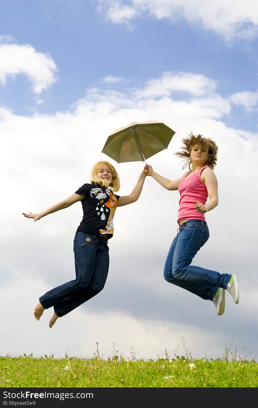 The two young girls jumping with a umbrella