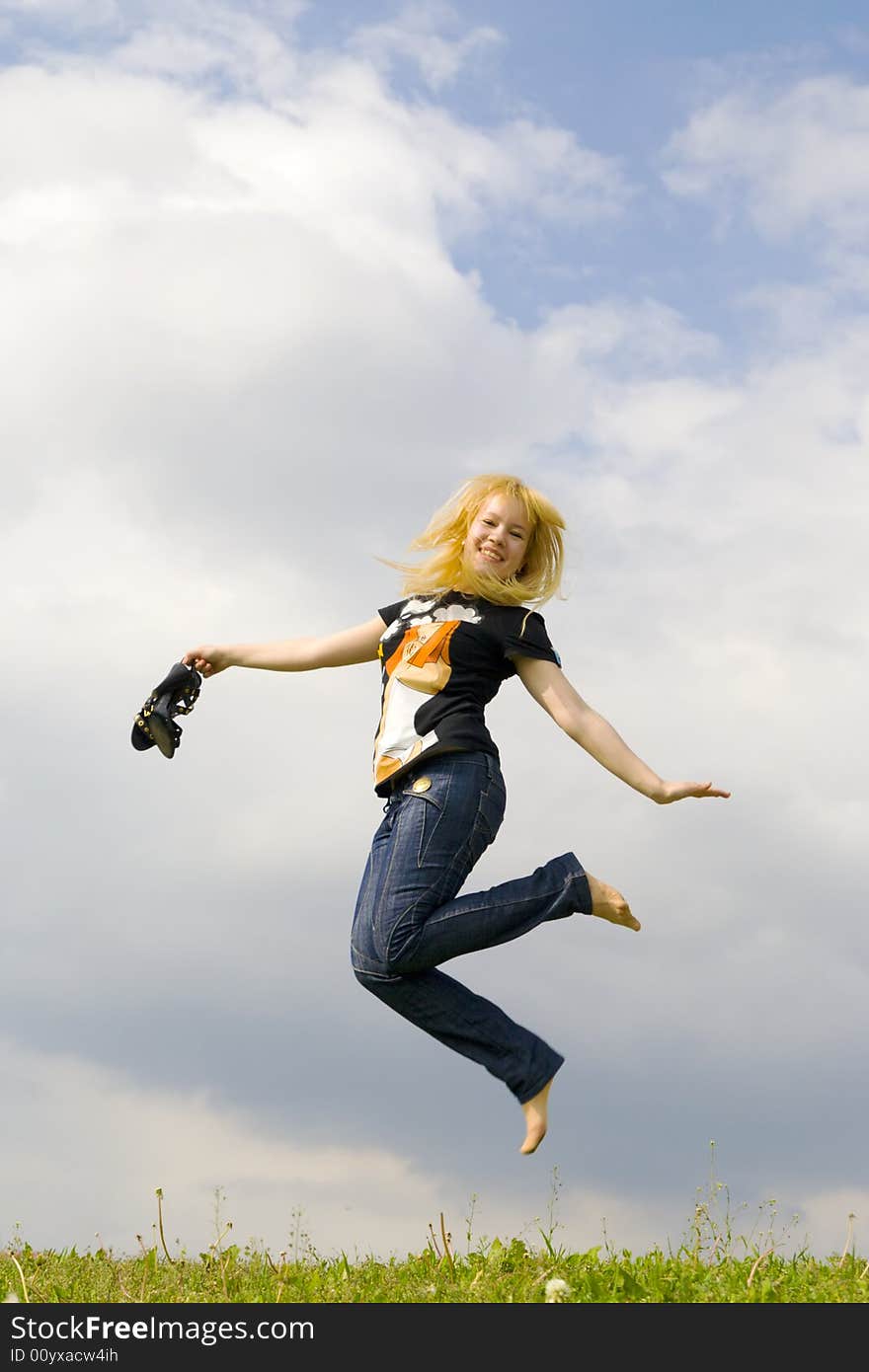 The young happy jumping girl on a background of the blue sky