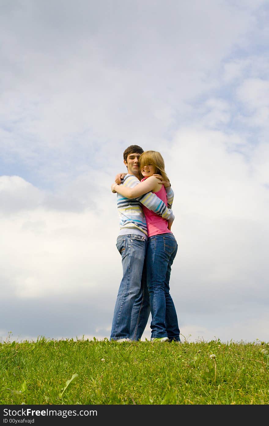 Young happy couple standing on a green grass