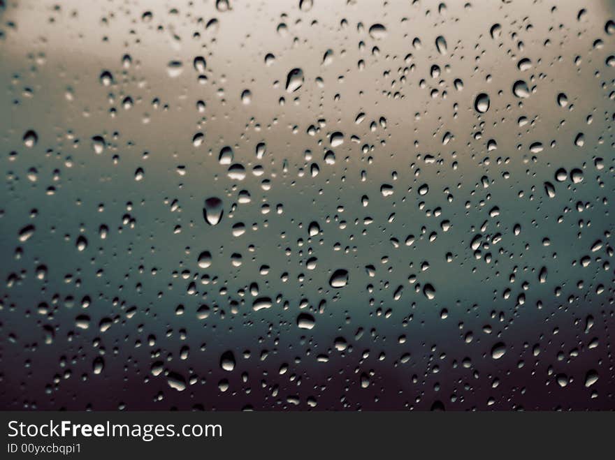 An abstract blend of colours of a window with rain droplets