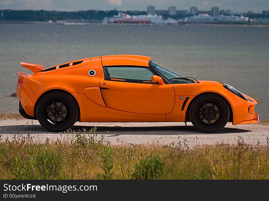 An orange supercar side view near the sea. An orange supercar side view near the sea