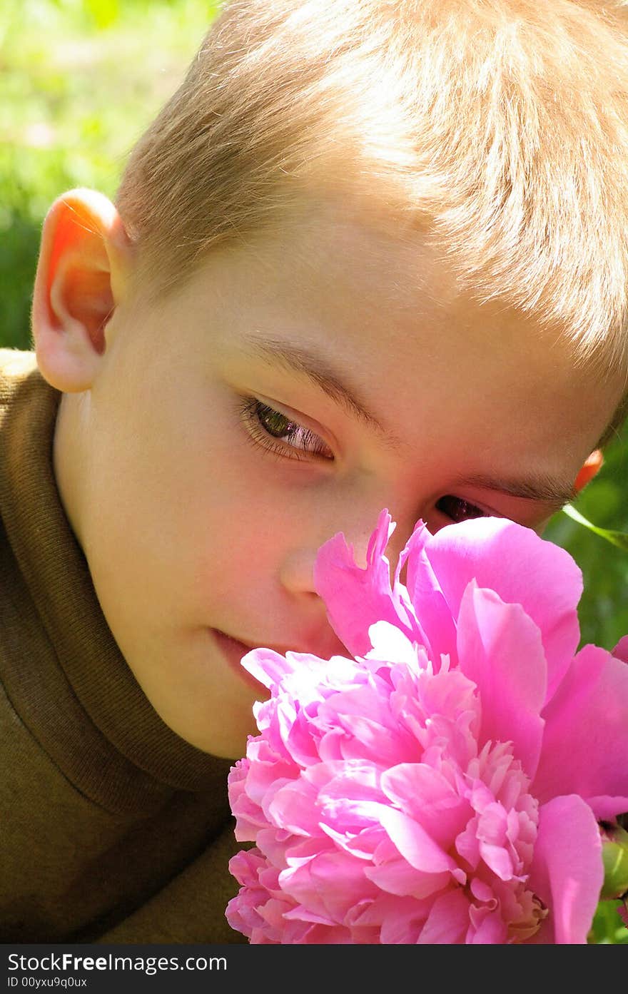 The boy of eight years next to the large pink flower. The boy of eight years next to the large pink flower