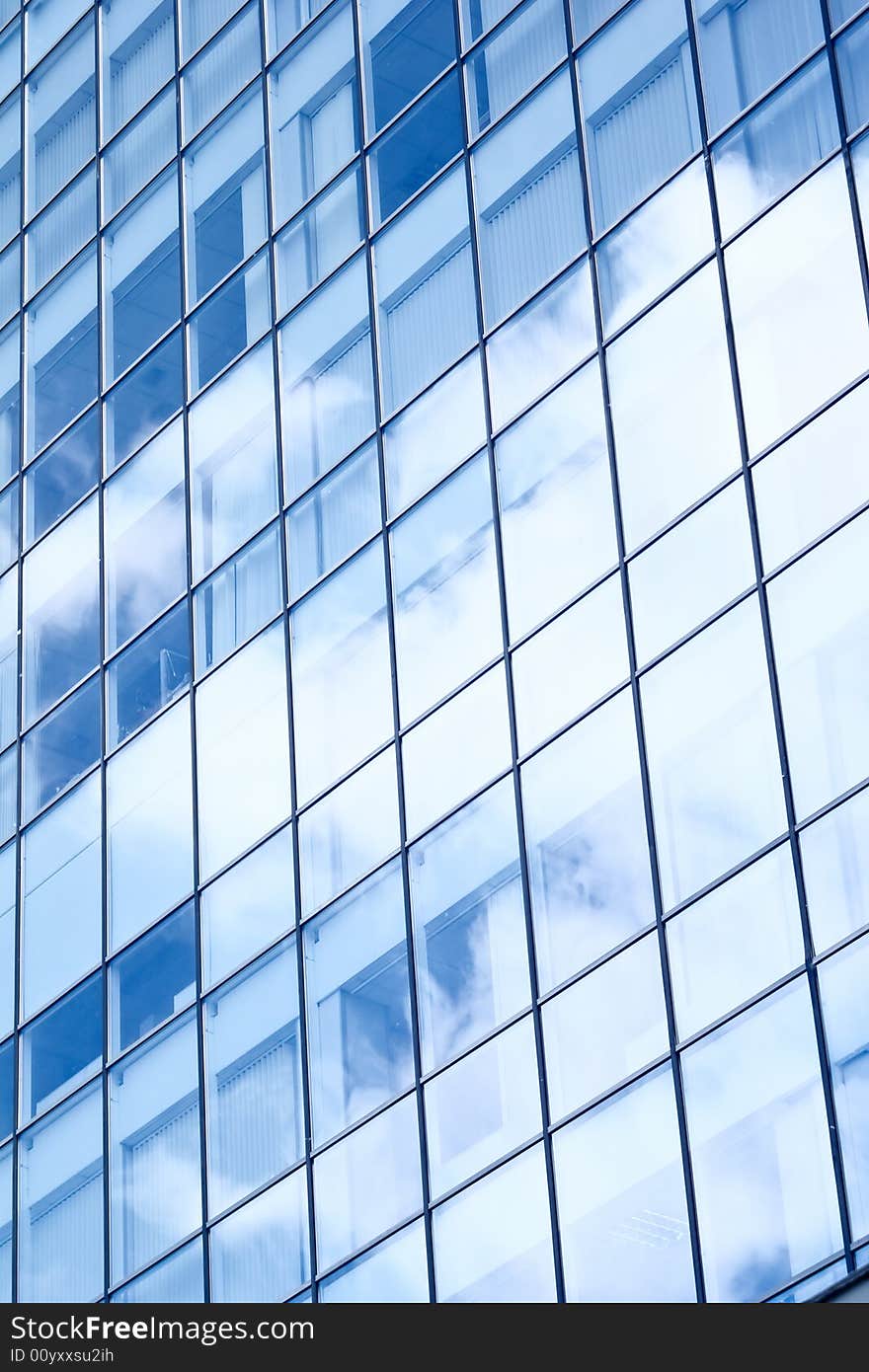 Windows in the office building with reflections of a clouds