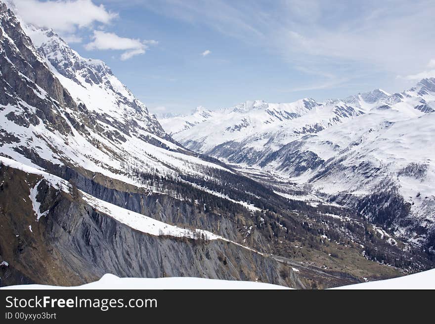 An alpine valley above Courmayeur in Val D'Aosta, Italy. It is in early spring and the snow is melting on the lower slopes. An alpine valley above Courmayeur in Val D'Aosta, Italy. It is in early spring and the snow is melting on the lower slopes.