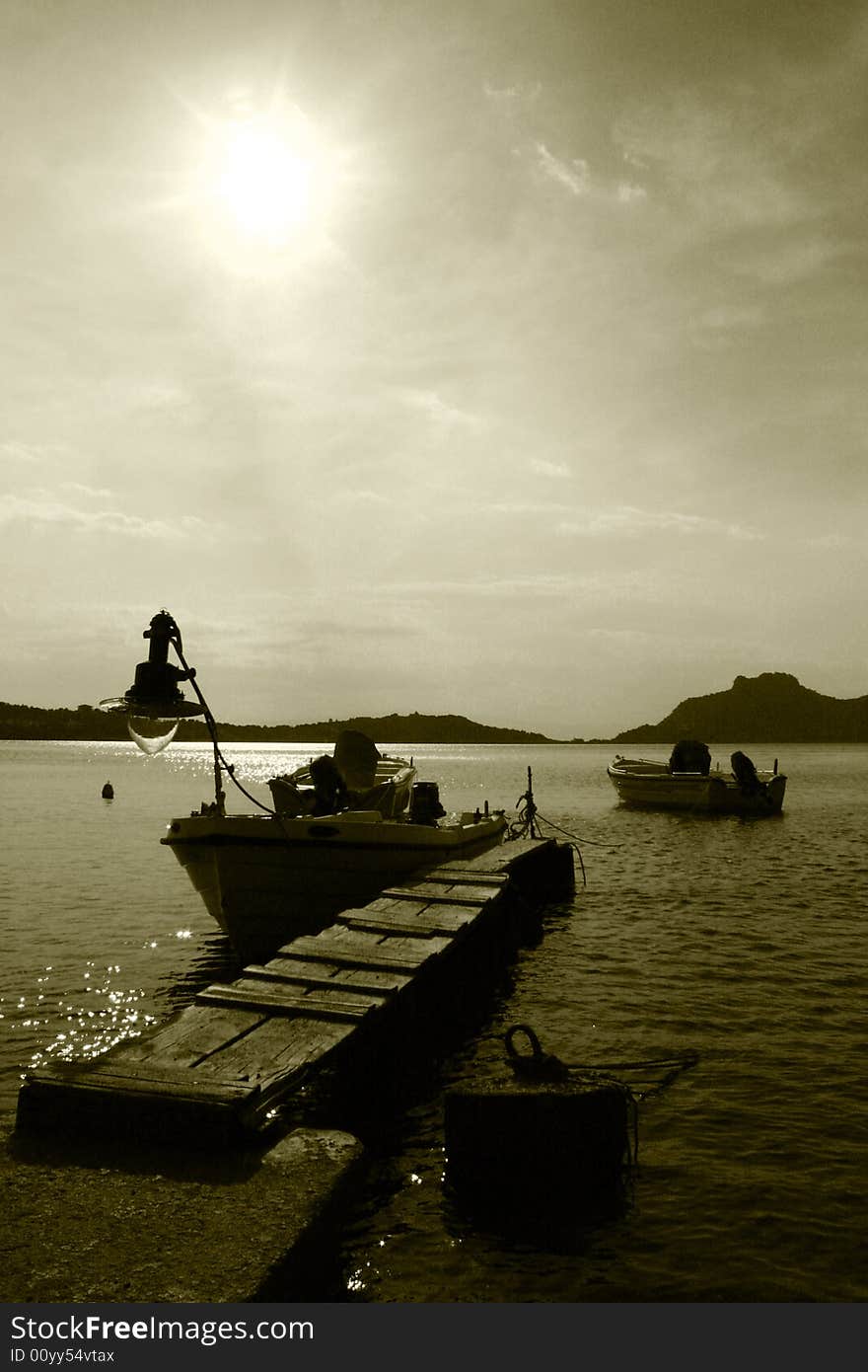 Little fishing boats near a wooden pier in a greek island