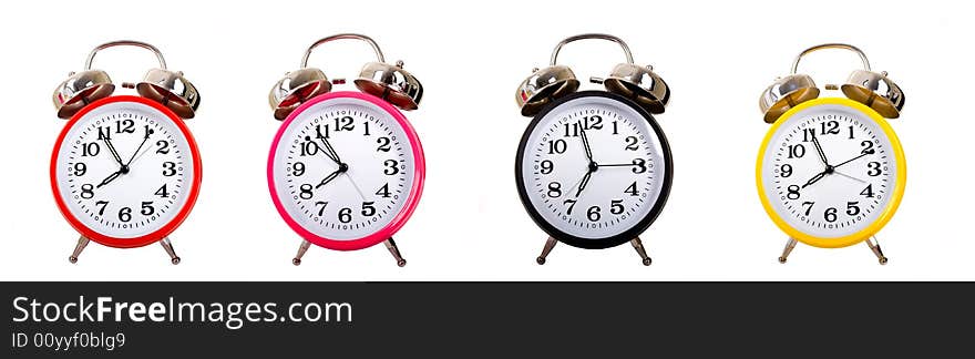 Several brightly colored traditional alarm clocks thrown on a white background