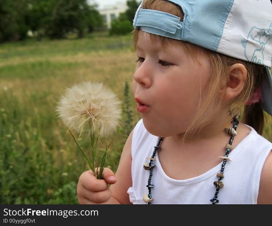 Little girl blowing dandelion seeds