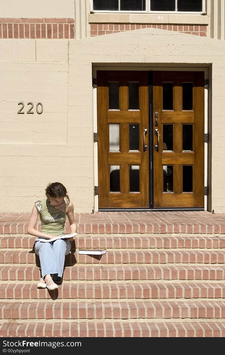 Young female student reading a book in front of class room