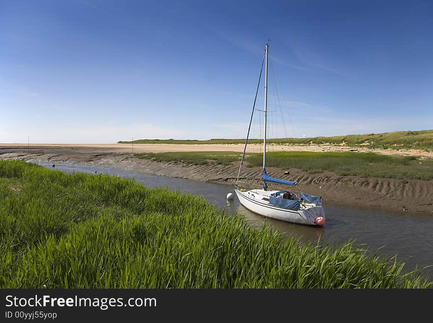 Yacht moored in river adjacent to sand dunes. Yacht moored in river adjacent to sand dunes