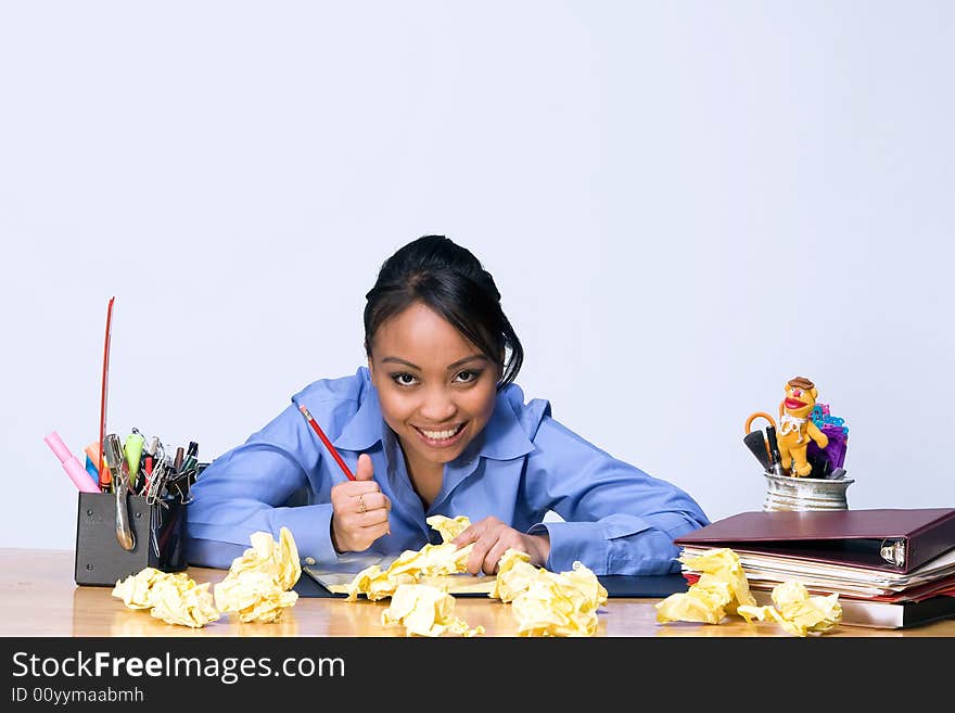 Teen girl looks stressed as she sits at a desk surrounded by crumpled paper, pens, pencils, and folders. Horizontally framed photograph. Teen girl looks stressed as she sits at a desk surrounded by crumpled paper, pens, pencils, and folders. Horizontally framed photograph