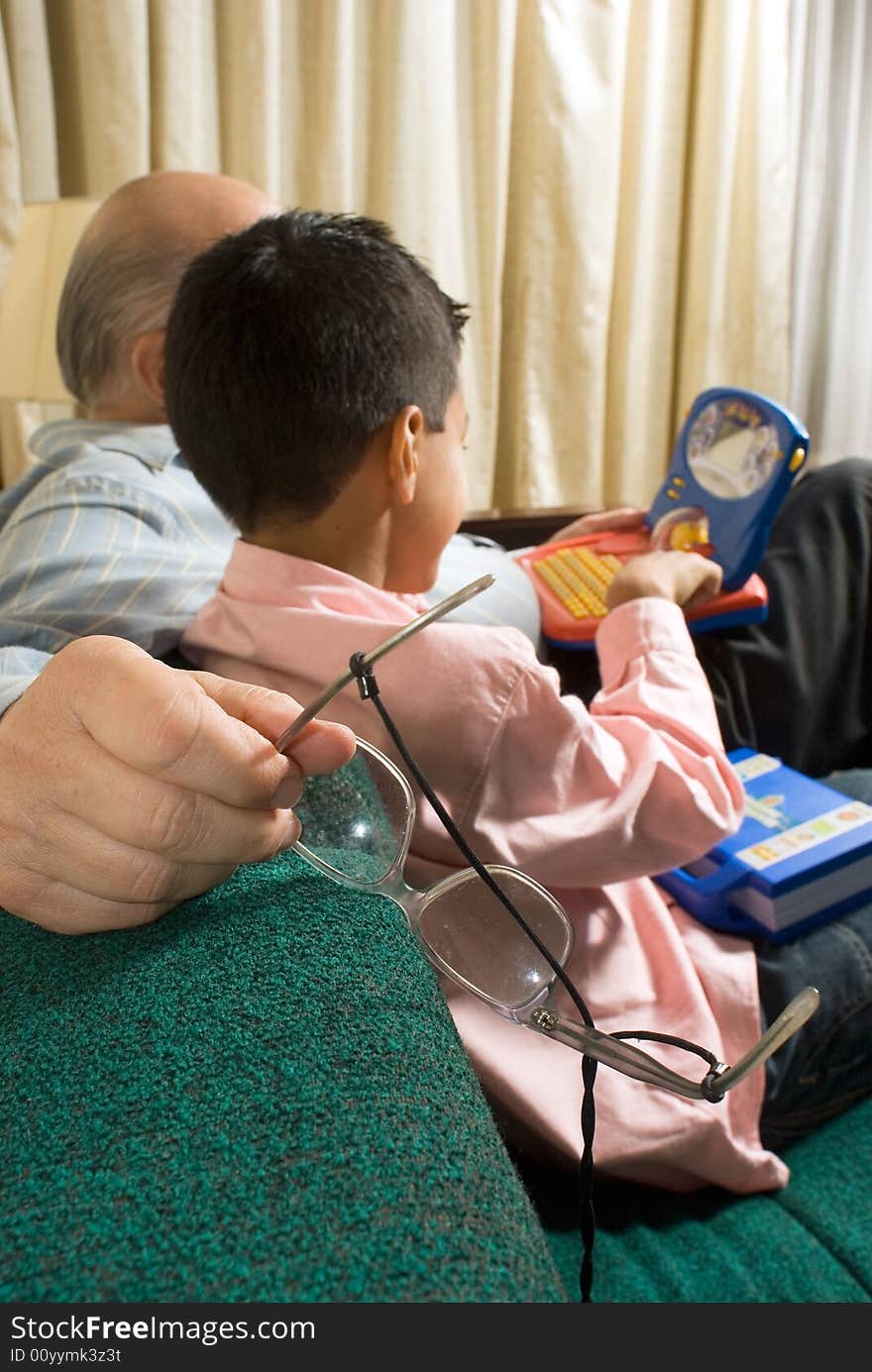 Grandfather and grandson sitting on couch playing