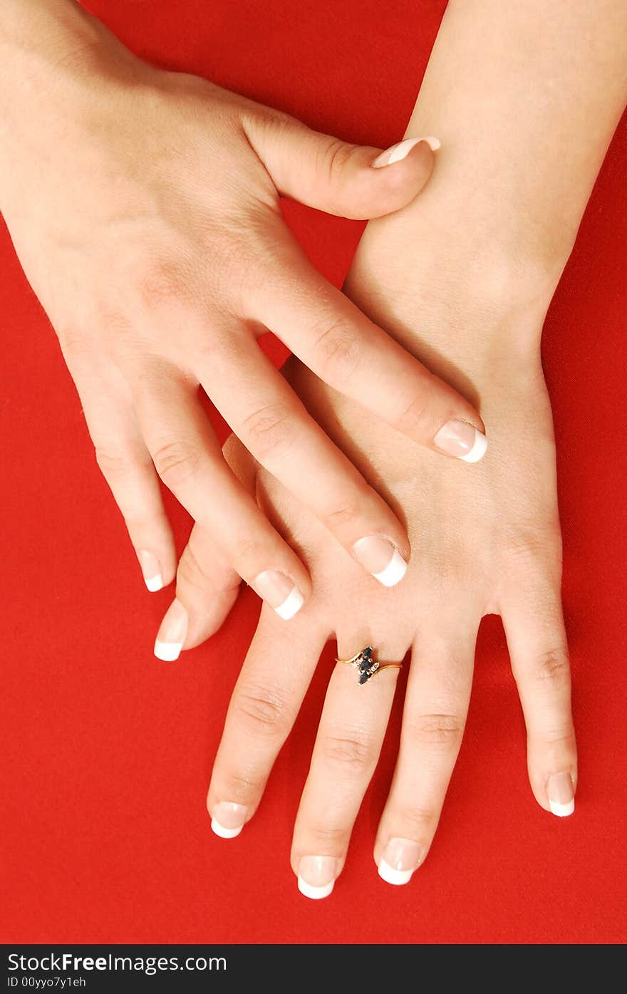 Close-up of the hands of a young woman on red fabric with nice finger nails and an small ring. Close-up of the hands of a young woman on red fabric with nice finger nails and an small ring.