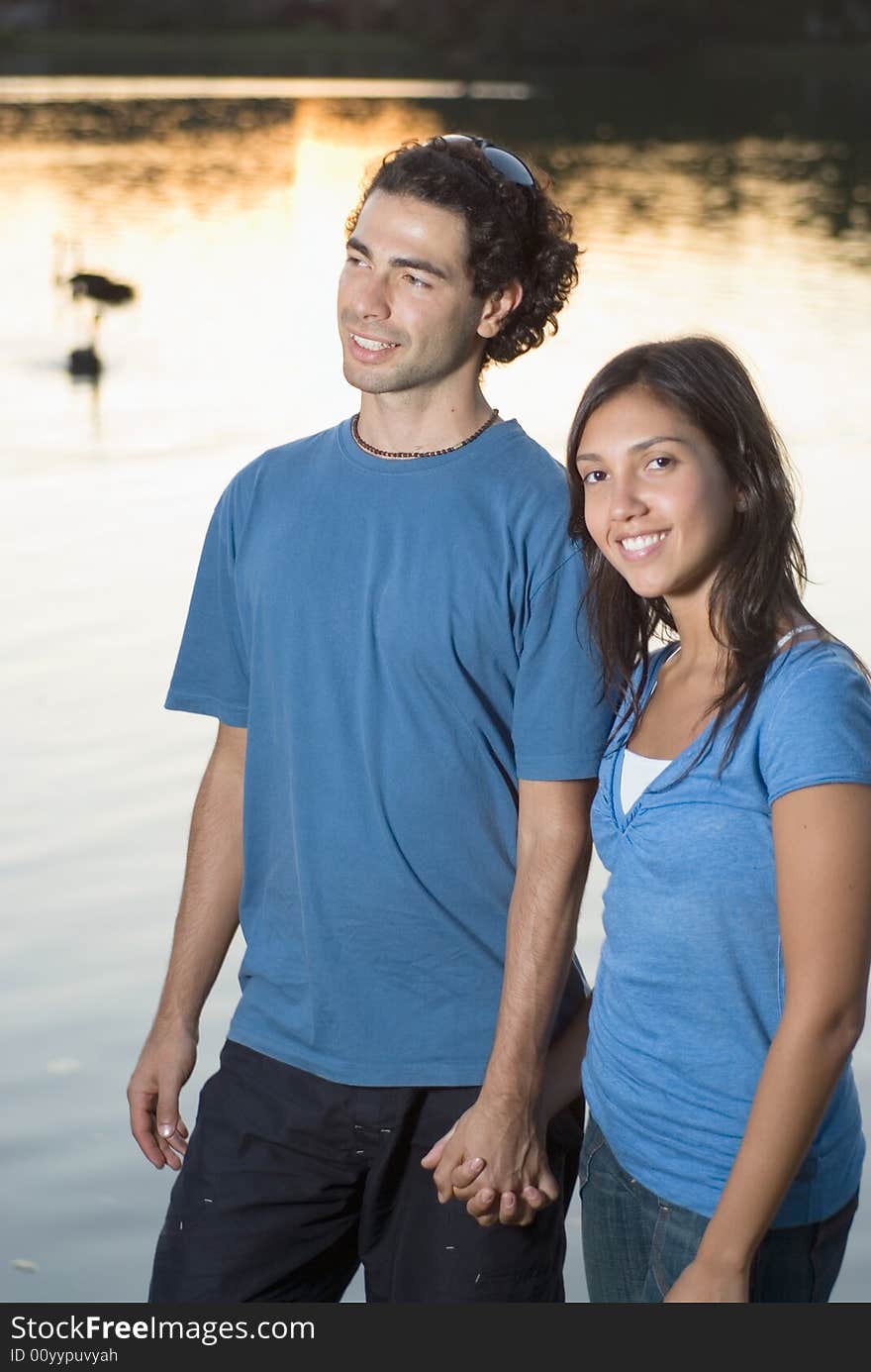 Happy Couple Holding Hands By A Pond - Vertical