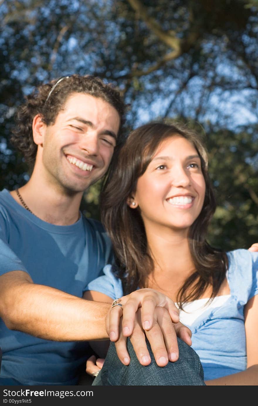 Close up picture of a happy couple sitting together outside. Vertically framed photograph. Close up picture of a happy couple sitting together outside. Vertically framed photograph