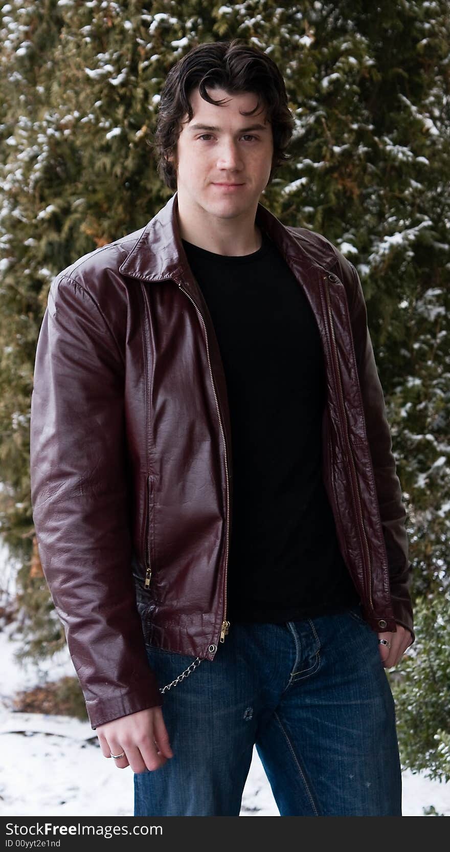 Man posing in front of snow covered trees.