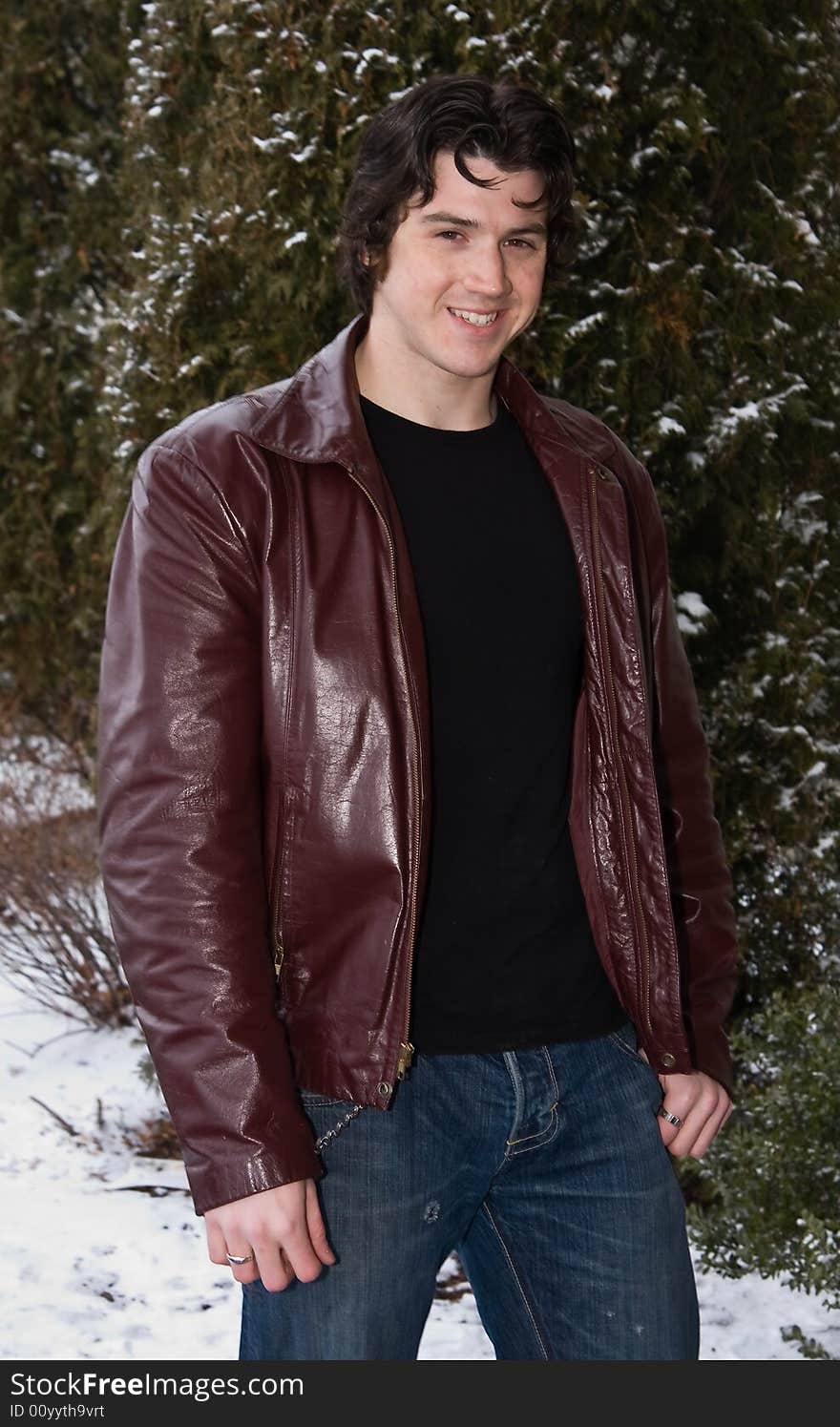 Man posing in front of snow covered trees.