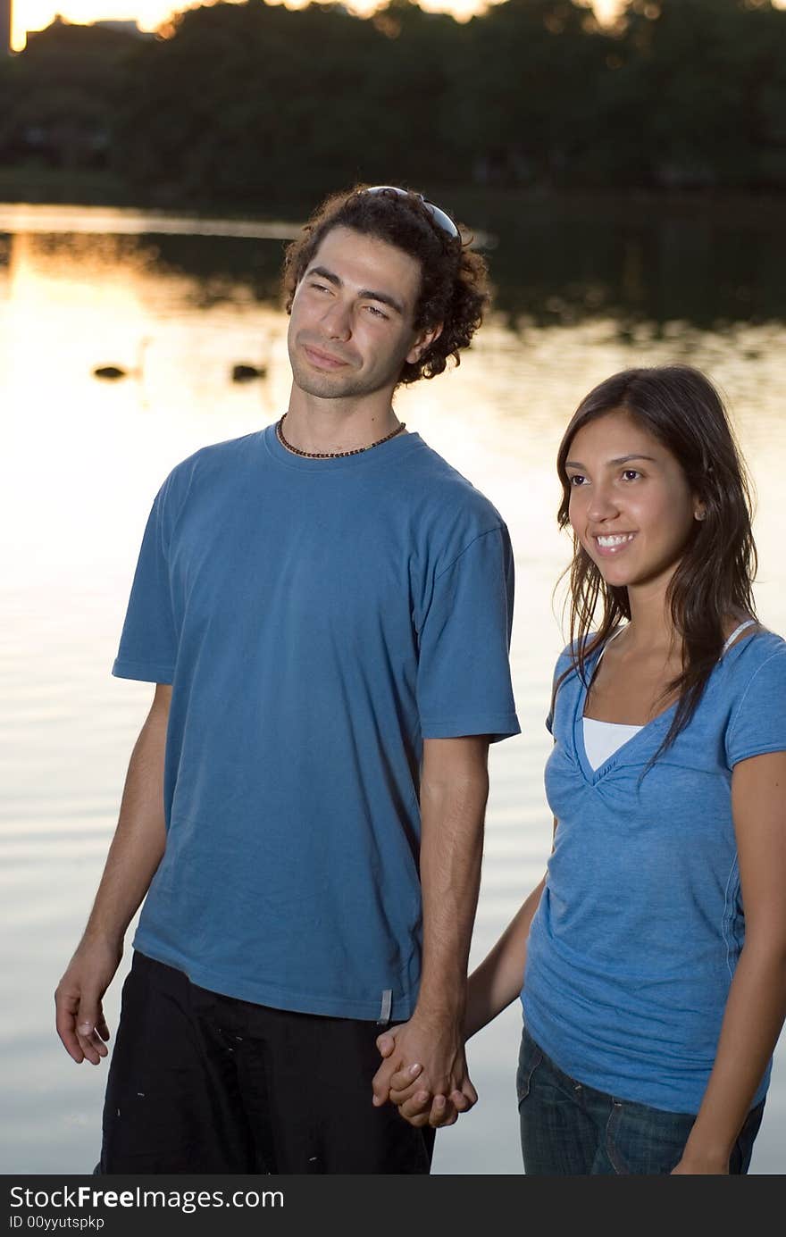 Happy Couple Holding Hands by a Pond - Vertical