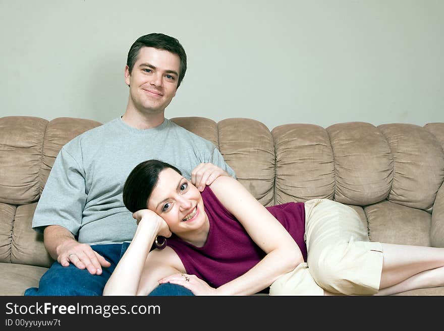 A smiling woman lying on a smiling man's lap sitting on a sofa. A smiling woman lying on a smiling man's lap sitting on a sofa.