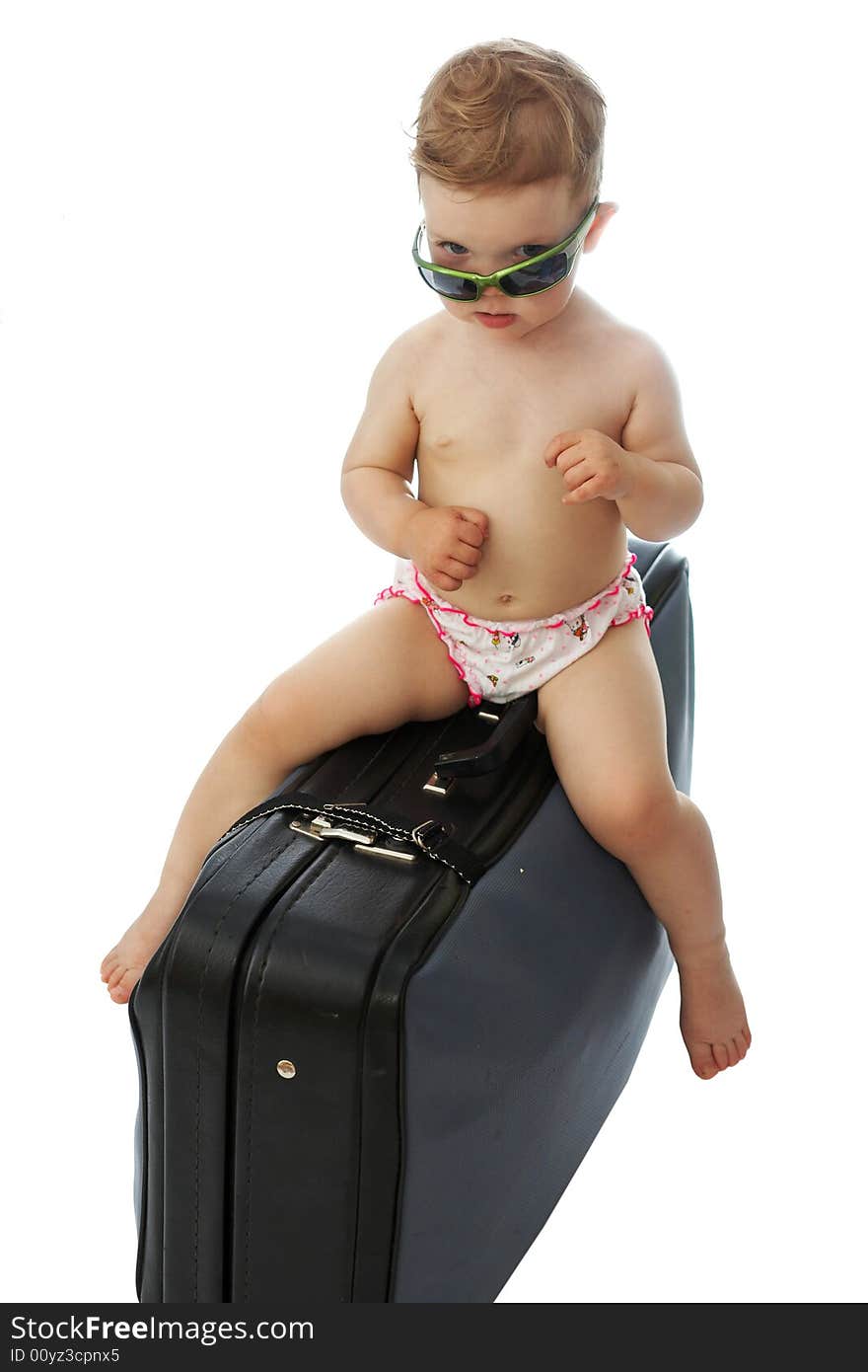 A baby on a valise looking from under goggles