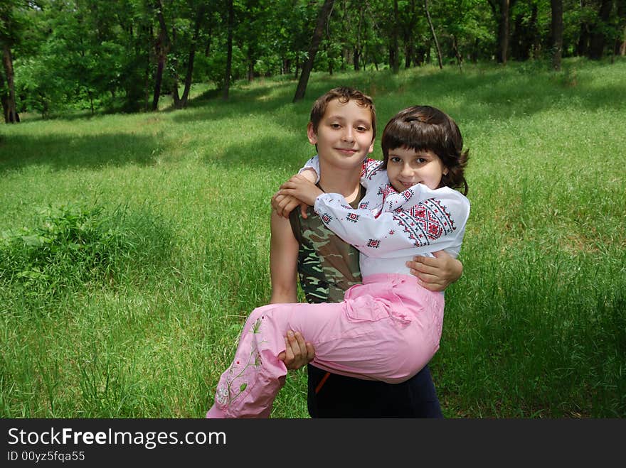 Boy hold girl in arms over green grass